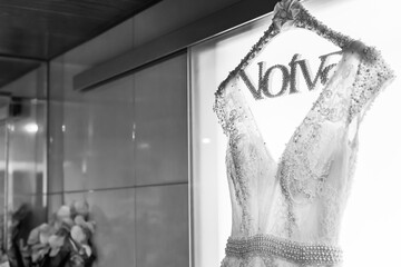 Black and white photo of wedding dress against glass door with backlight. Space for text