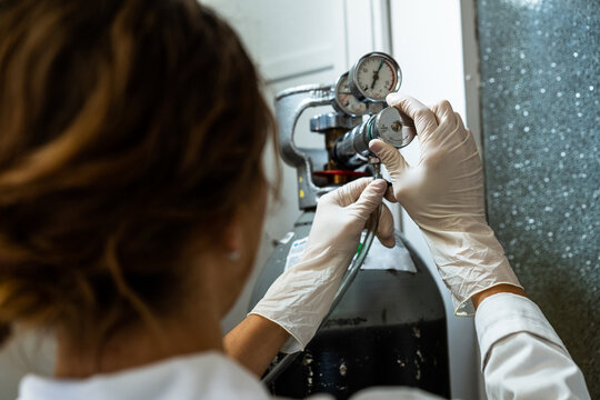 Female technician in gloves adjusting a barometer of a nitrogen cylinder or compressed air