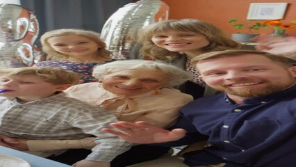 POV vertical shot of happy family smiling and waving on camera while taking selfie or video calling on grandma birthday party - Powered by Adobe