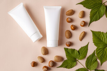 Obraz na płótnie Canvas Mockup for a cosmetic brand. The concept of eco organic products, minimalism style. Cosmetic container on a beige background, next to natural hazelnuts. Face and body skin care. Place for text