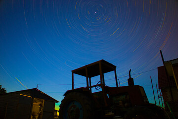Time interval stars on the background of an old tractor and a house
