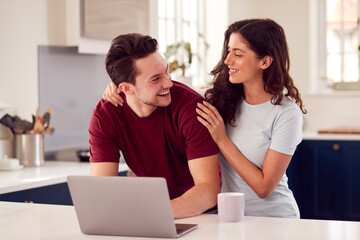 Loving Transgender Couple At Home Together Looking At Laptop On Kitchen Counter