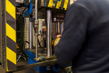 Automation hydraulic press stamping machine production line. Industrial metalworking machines. A worker presses a die in a hydraulic press.
