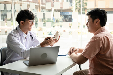 Obraz premium Male doctor discussing with the patient explaining symptoms of the disease after diagnosis checking while recommending treatment methods in clinic