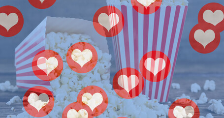 Image of heart icons flying over popcorn in red and white striped tubs - Powered by Adobe