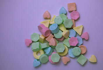 Colorful pastel candies on a light purple background.