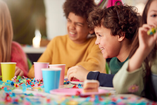 Children Sitting At Table Friends Celebrating At Birthday Party With Friends At Home