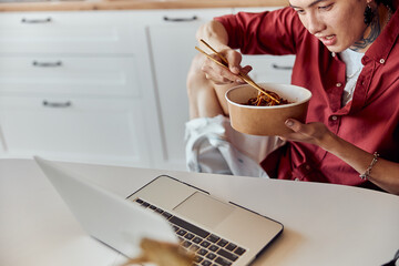 Happy man eating wok udon with chopsticks at home