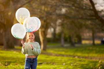 Portrait Of Girl Outdoors In Countryside Playing With Balloons