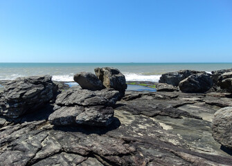 Fototapeta na wymiar Linda praia com grandes pedras, com céu azul e linda paisagem ao fundo fotografado em Vitória no estado do Espírito Santo, Brasil.