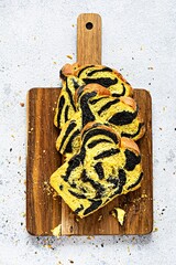 Unusual pumpkin marbled (tiger print) bread with cuttlefish ink, braided on a wooden board on a light background. Useful home baking.