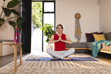 Non-binary trans woman practicing yoga and meditation sitting on yoga mat at home