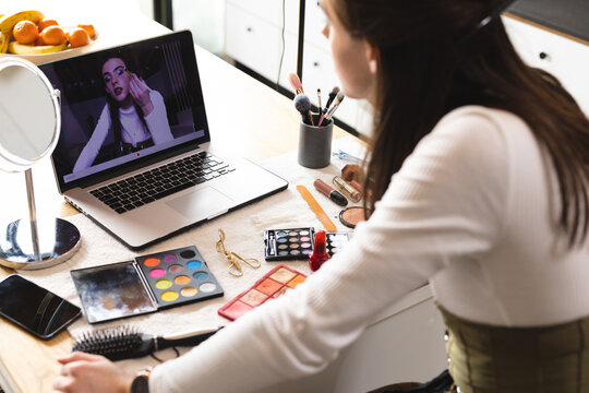Non-binary trans woman beauty make up artist vlogger recording makeup tutorial on laptop
