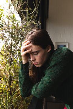 Stressed non-binary trans woman holding her head in the balcony at home