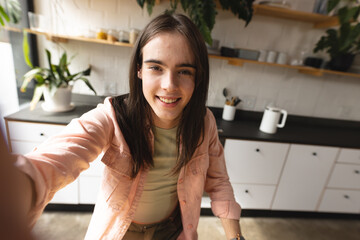Portrait of non-binary trans woman smiling looking at the camera in the kitchen at home - Powered by Adobe