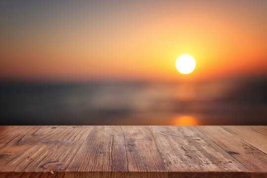 Wooden table and blurred sunset background. Summertime and vacation