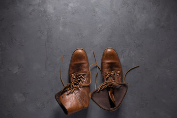 Brown leather boots on abstract cement floor background texture. Old shabby boot shoes
