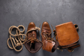 Old leather boots and travel stuff set on floor background texture. Trip goods as concept idea