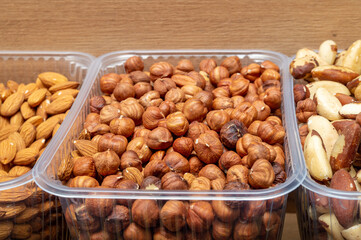 hazelnuts in a plastic container next to other nuts