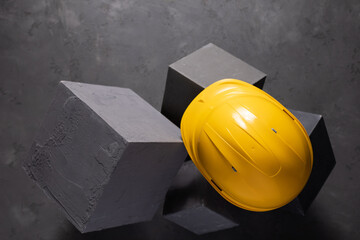 Concrete cube and construction helmet on floor background texture. Cement block and hardhat