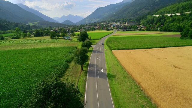 Cars riding on a mountain road near ripe fields