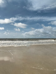 Praia de areias escuras sob céu azul com muitas nuvens, localizada em São Luis, Maranhão, Brasil. - obrazy, fototapety, plakaty