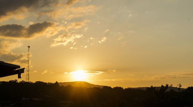 Pôr do sol entre montanhas, torres e céu limpo com nuvens, visto em sítio localizado em Juatuba, Minas Gerais, Brasil.