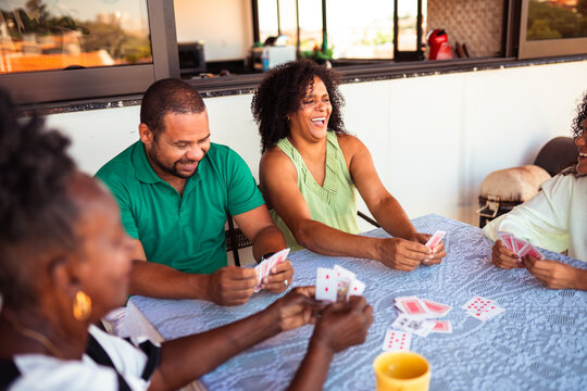 Família reunida jogando baralho na mesa da sala