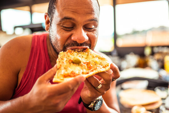 Homem comendo com as mãos uma saborosa pizza