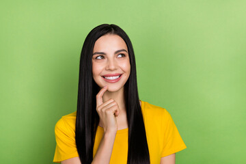 Photo of positive pretty person finger touch chin look interested empty space isolated on green...