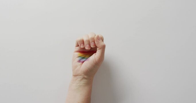 Video of hand of caucasian man with rainbow flag on white background