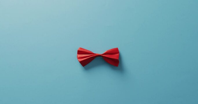 Video of red bow tie lying on blue background