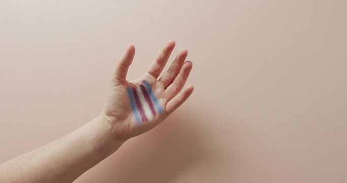 Video of hand of caucasian man with rainbow flag on pink background