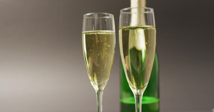 Video of champagne in glasses and bottle on grey background