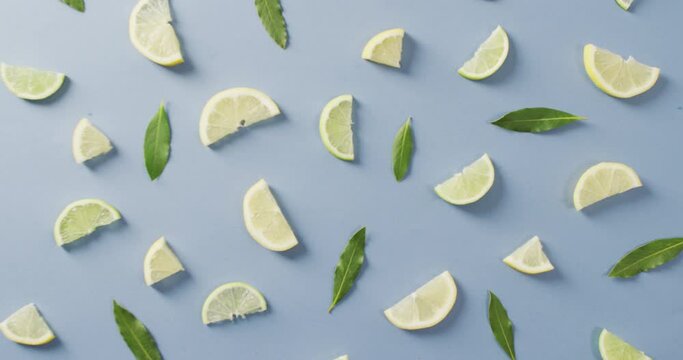 Video of slices of lemon and mint leaves lying on blue background