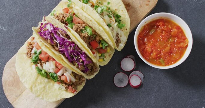 Video of freshly prepared tacos lying on board on grey background