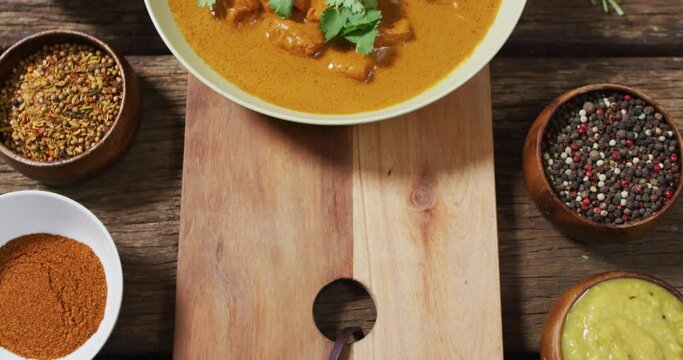 Video of freshly prepared curry in bowl lying on board on wooden surface