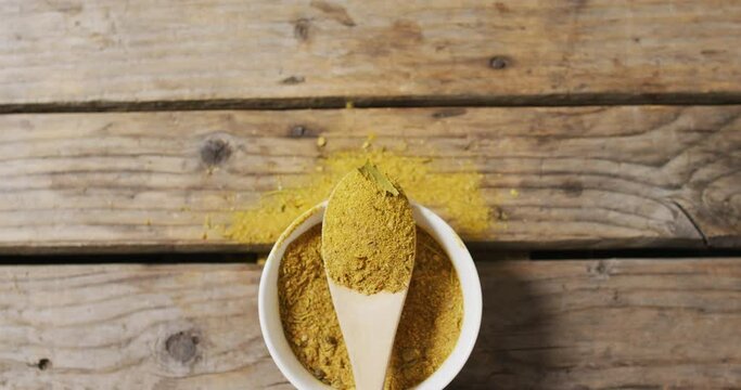 Video of spoon with tumeric seasoning lying on wooden surface