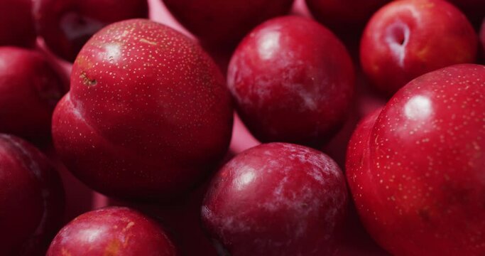 Video of fresh plums lying on pink surface