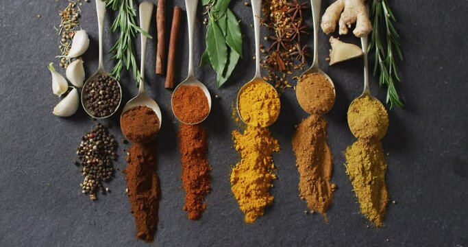 Video of spoons with diverse seasonings and herbs lying on grey background