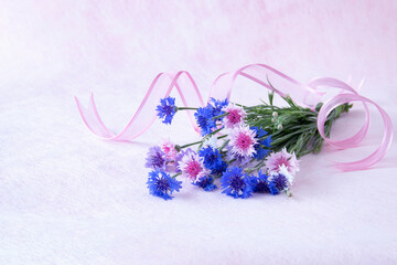 ピンクのリボンとピンクや青の矢車草の花束(ピンクバック）