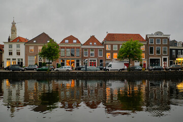 Fototapeta na wymiar Haarlem, Netherlands - May 23. 2022: Panoramic view of traditional Dutch houses in a row lining the river Sparne in the summer.