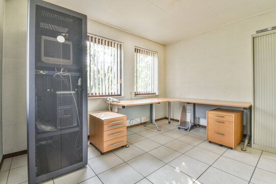 Office room with wooden furniture and computer inside of mesh door cabinet