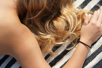 Beautiful blonde hair woman relax on striped beach towel 