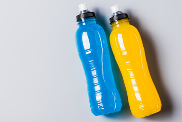 Isotonic energy drink copy space  grey background. Bottles with blue and yellow water sport beverage flat lay.