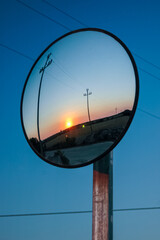 spectacular sunset reflected in a circular mirror placed on a telephone pole