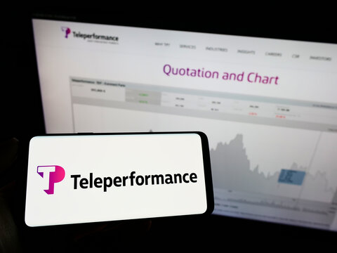 Stuttgart, Germany - 05-21-2022: Person holding mobile phone with logo of French company Teleperformance SE on screen in front of business web page. Focus on phone display.