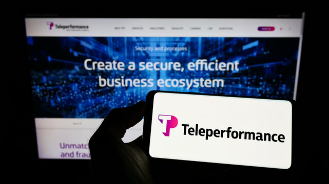 Stuttgart, Germany - 05-21-2022: Person holding smartphone with logo of French company Teleperformance SE on screen in front of website. Focus on phone display.
