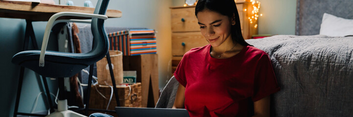 Young hispanic woman working with laptop while sitting on floor