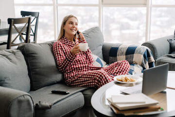 Young white woman talking on cellphone while having breakfast at home